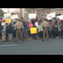 Group of protesters hold up signs while MD State Troops observe the crowd